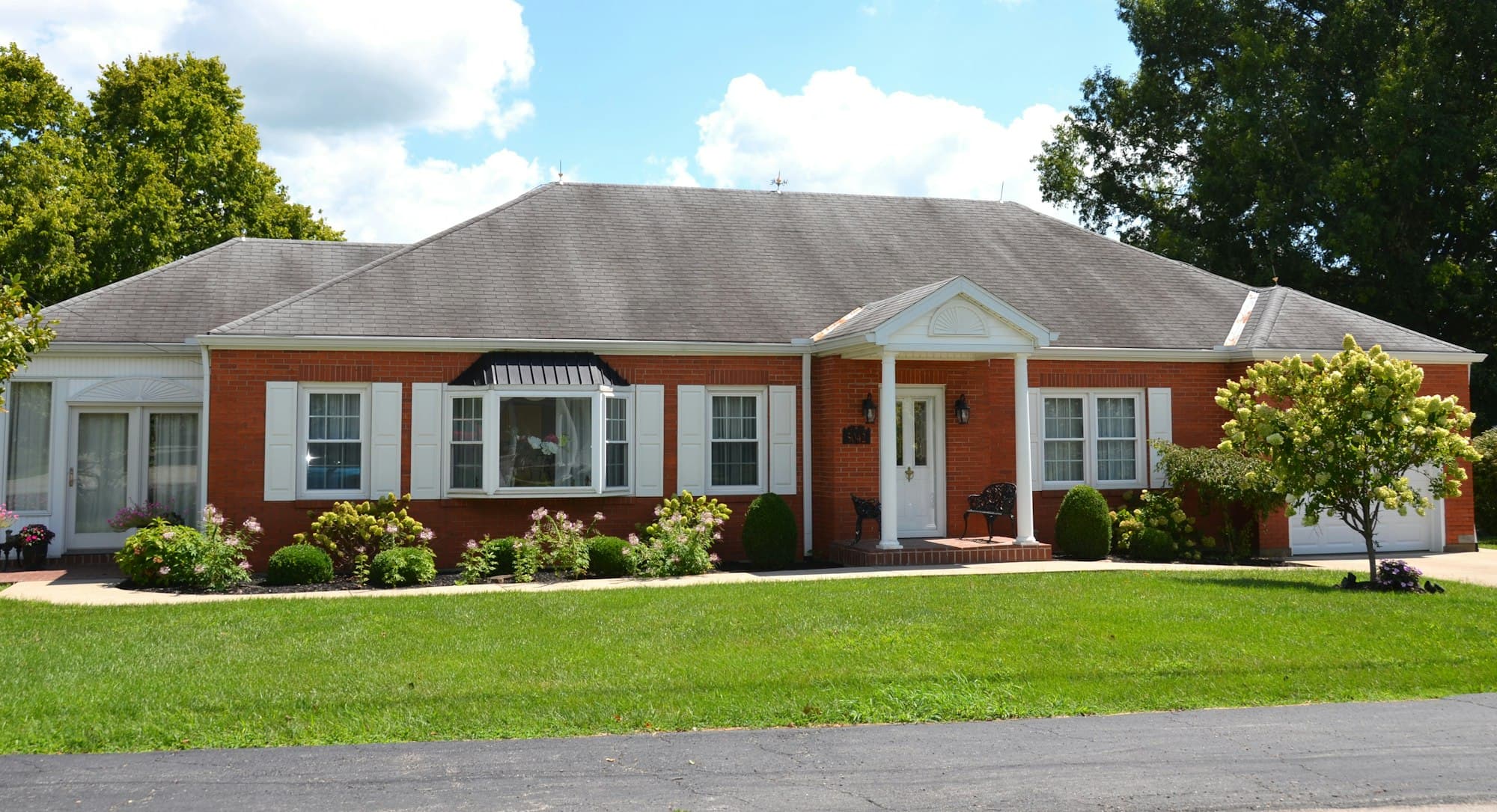 Single-story brick home with a wide, freshly treated front lawn