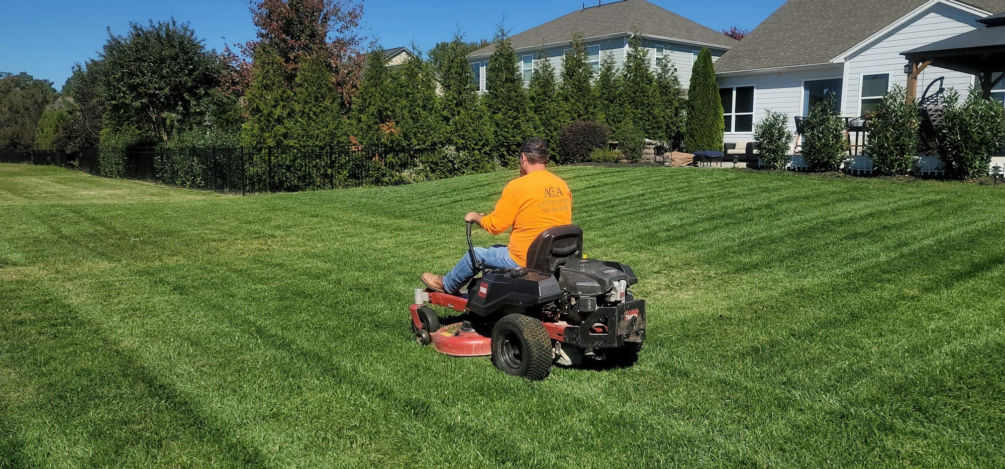 Zero-turn mower laying stripes across a suburban lawn