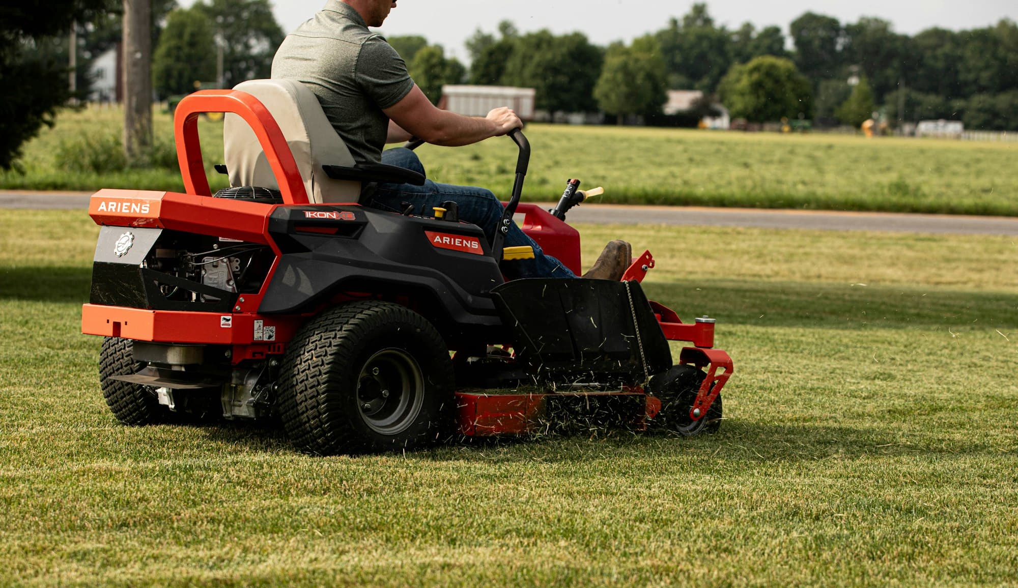Operator on a zero-turn mower working an open lawn