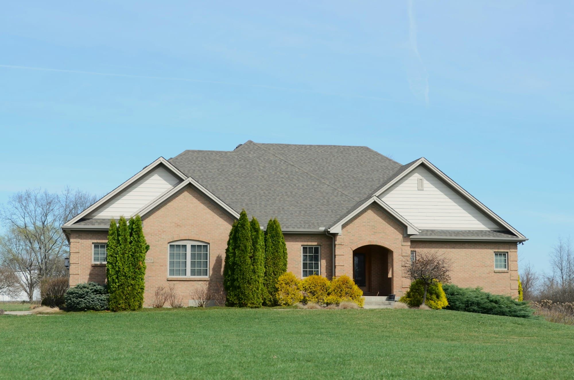 Brick ranch home on a flat lot, foundation plantings along the front